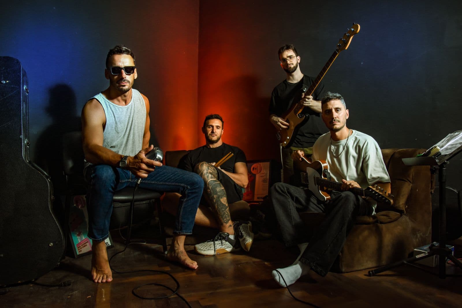 HOSTEL Argentine rock band in a studio with guitars, bass, drumsticks and a vintage microphone under red and blue stage lighting